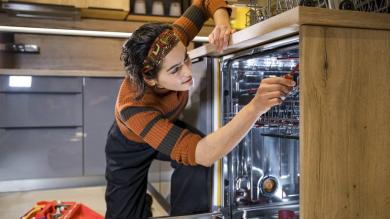 Frau repariert eine Spülmaschine in der Küche 