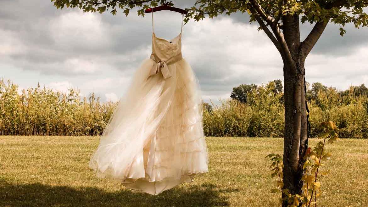 Ein Brautkleid, das mit einem Kleiderbügel an einem Baum hängt