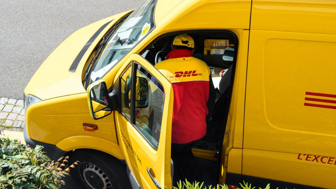 Paketbote von DHL mit Zustellfahrzeug