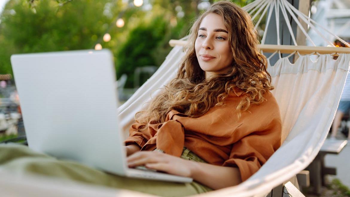 Frau mit Laptop in Hängematte