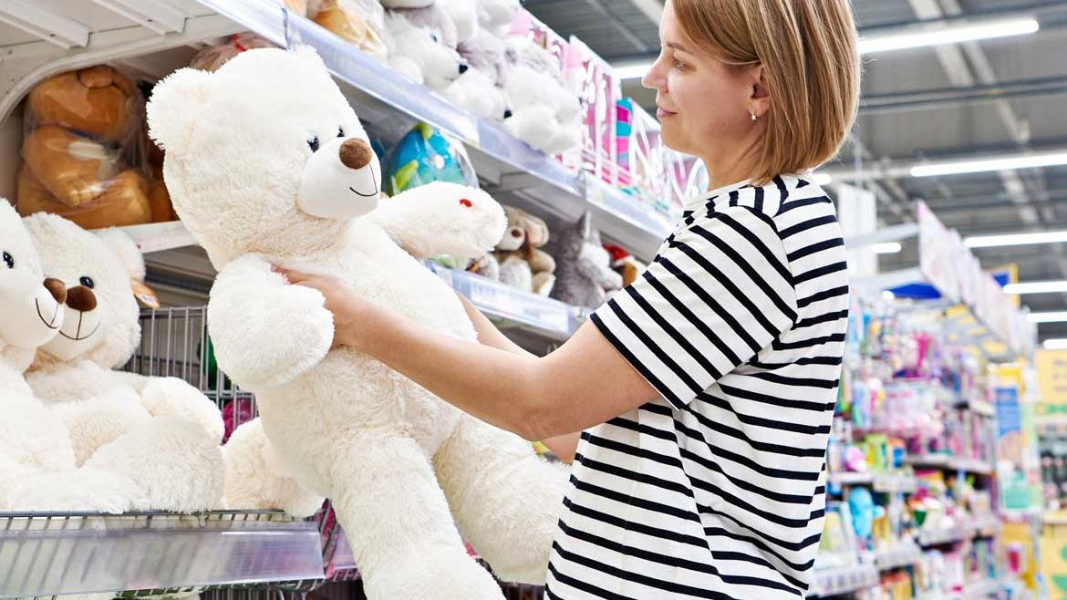 Frau kauft Teddybär in Spielzeugladen