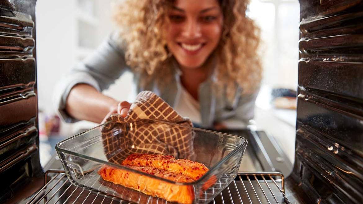 Frau schiebt Lachs in Backofen
