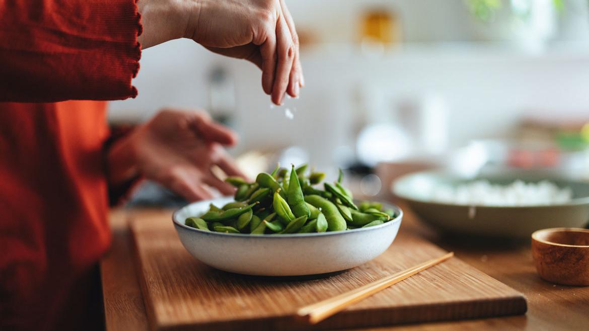Frau würzt Edamame (Sojabohnen)