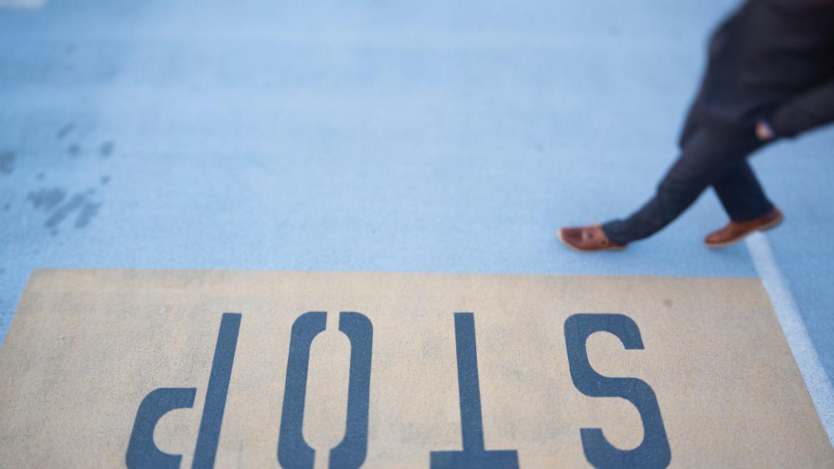 Fußgänger läuft über Straße mit Stop-Schriftzug