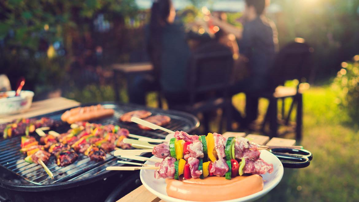 Grill mit Fleisch und Menschengruppe im Hintergrund