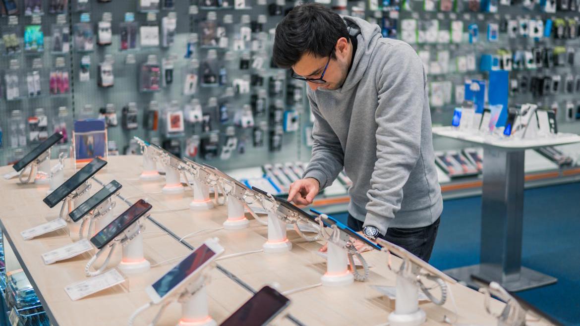 Mann schaut auf Smartphone in Shop
