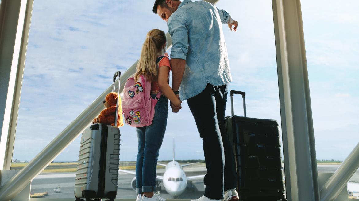 Vater und Tochter für Pauschalreise mit Koffern am Flughafen 
