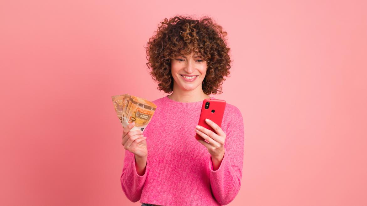 Frau vor rosa mit Geldscheinen und Handy in der Hand 