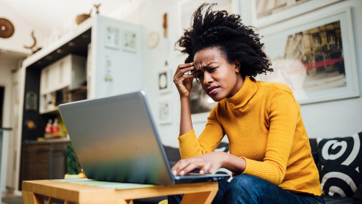 Frau sitzt grübelnd vor Laptop 