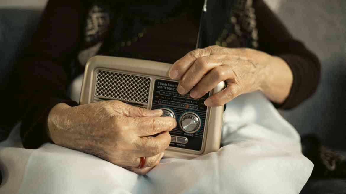 Alte Frau hält altes Radio in den Händen 
