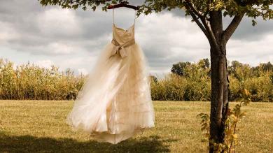 Ein Brautkleid, das mit einem Kleiderbügel an einem Baum hängt