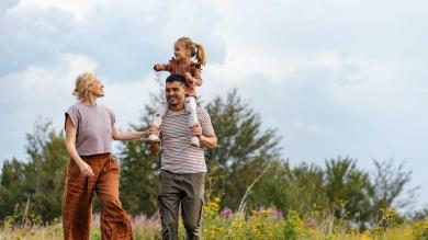 Familie mit Kind geht über Wiese