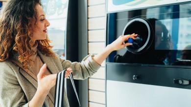 Frau gibt Flasche am Pfandautomaten zurück