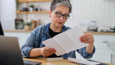 Frau liest Brief in der Küche