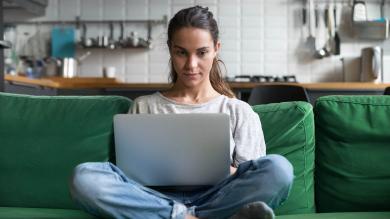 Frau mit Laptop auf grünem Sofa