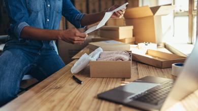Frau öffnet Paket und hält Rechnung in der Hand