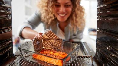 Frau schiebt Lachs in Backofen