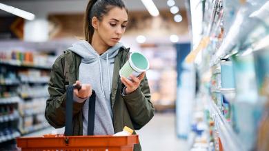 Junge Frau schaut auf Packung im Supermarkt