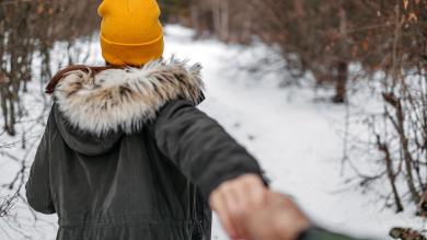 Laufende junge Frau mit Jacke und Pelzkapuze - von hinten zu sehen