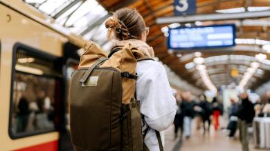 Junge Frau mit Rucksack am Bahnhof