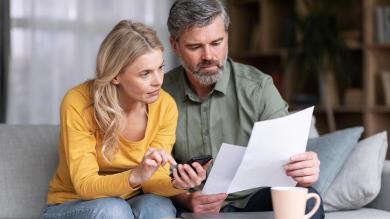 Verheiratetes Paar mittleren Alters plant gemeinsam Budget, liest Papiere und berechnet Ausgaben