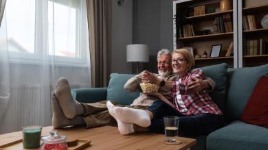 Paar sitzt auf Sofa und schaut Film mit Popcorn