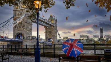 Person mit Regenschirm sitzt an Tower Bridge in London