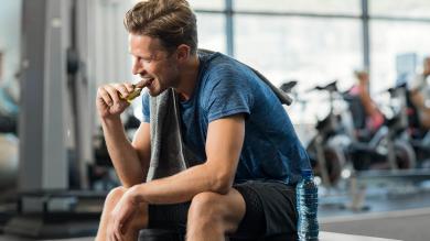 Sportler in Sportkleidung isst Energieriegel im Fitnessstudio