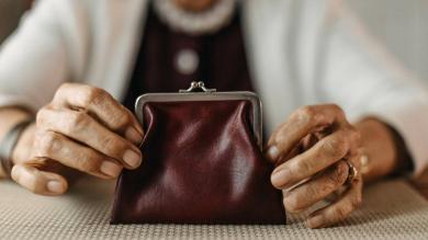 Ältere Dame hält Geldbörse in den Händen 