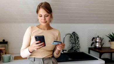 Junge Frau zahlt mit Girokarte und Handy 