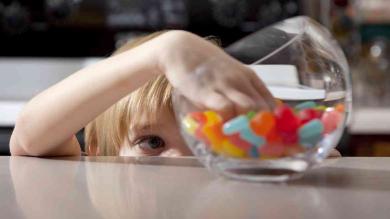 Kind greift in ein Glas mit Weingummi 
