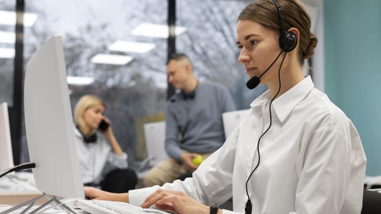 Frau im Callcenter mit Kopfhörer und Mikrofon