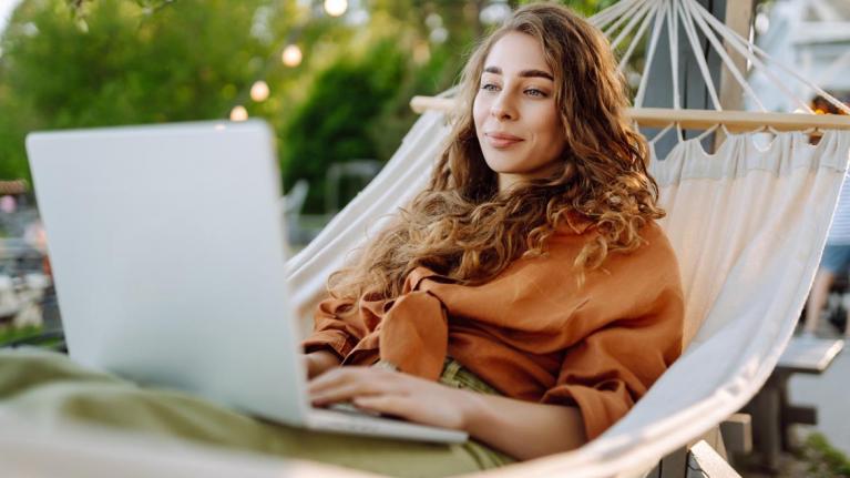 Frau mit Laptop in Hängematte