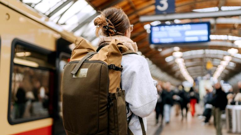 Junge Frau mit Rucksack am Bahnhof