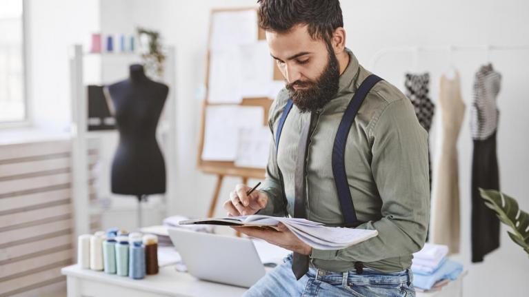 Mann mit Skizzenheft in Modeatelier