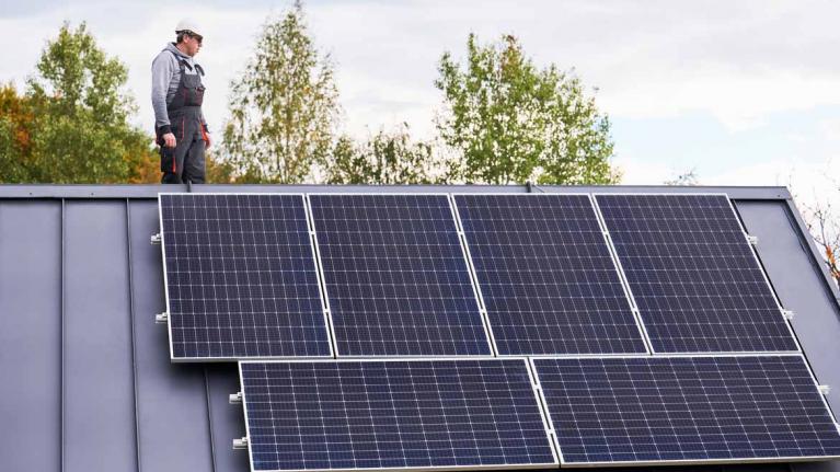 Techniker arbeitet an Photovoltaikanlage und steht auf Dach eines Hauses