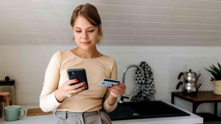 Junge Frau zahlt mit Girokarte und Handy 