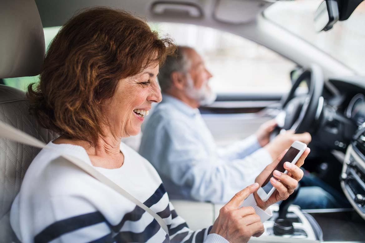 Ältere Frau mit Smartphone im Auto