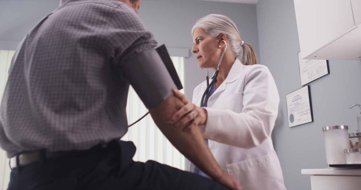 Ärztin misst Blutdruck bei Patient