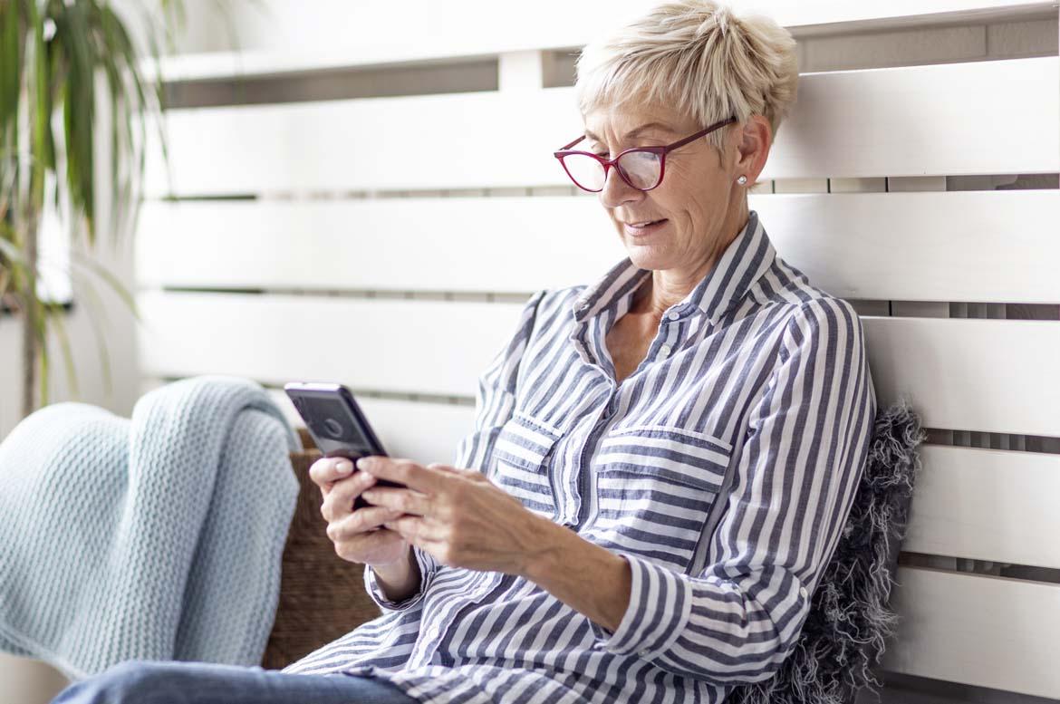 Ältere Frau mit Smartphone tippt