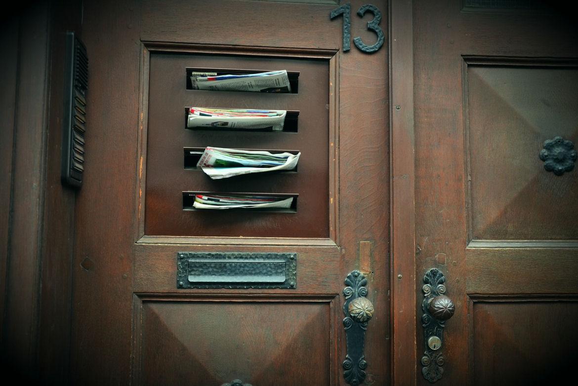 Mehrere Briefschlitze in Tür mit Zeitungen und Post