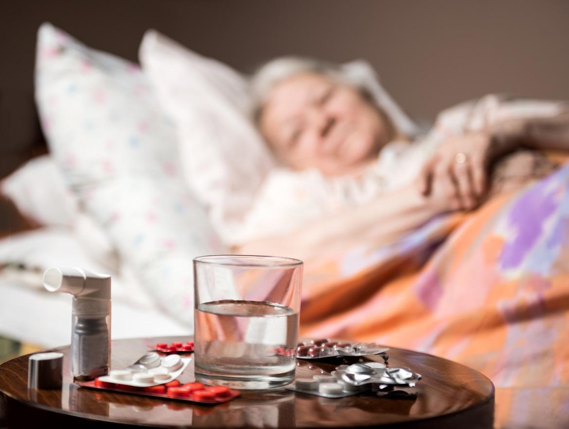 Frau im Bett mit Tabletten auf Tisch