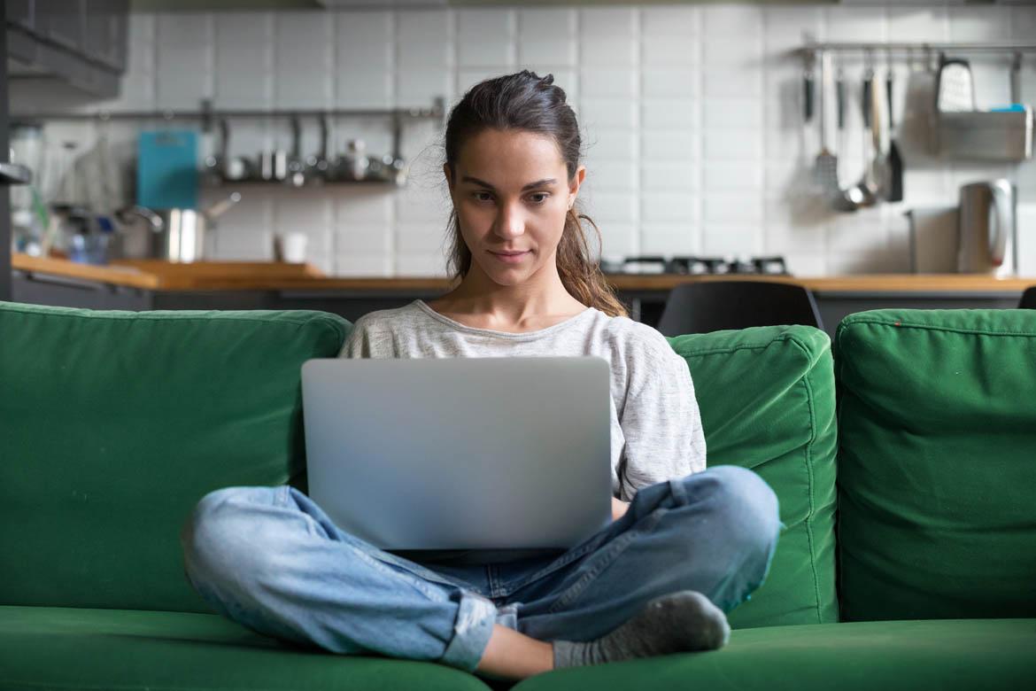 Frau mit Laptop auf grünem Sofa