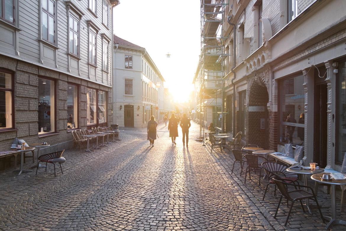 Menschen laufen in Fußgängerzone der Sonne entgegen