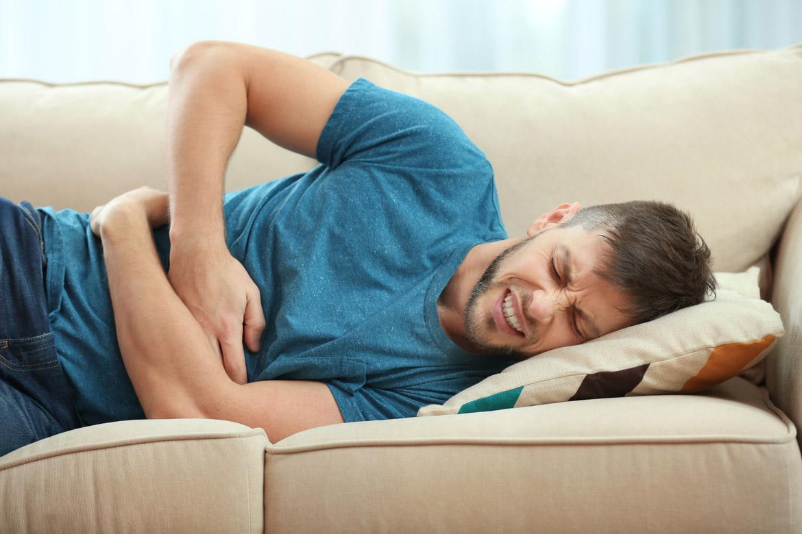 Mann mit Bauchschmerzen auf Sofa