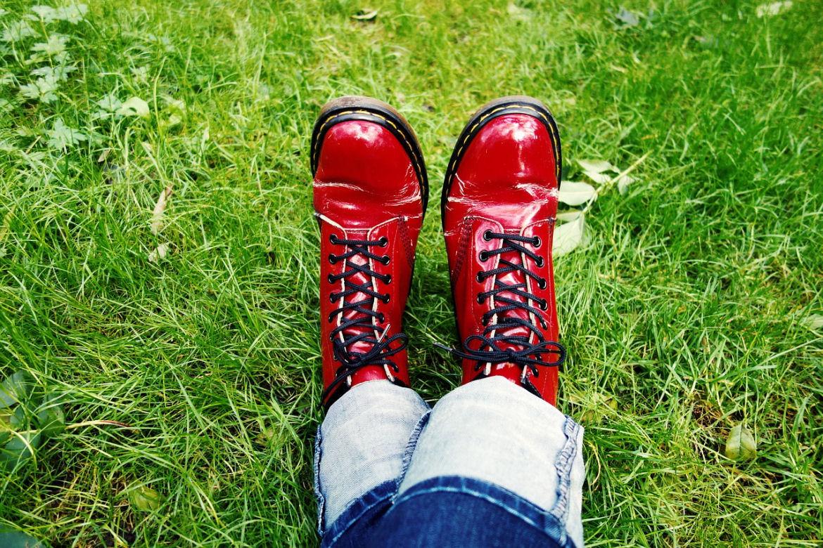 Zwei Beine mit roten Schuhen in grünem Gras