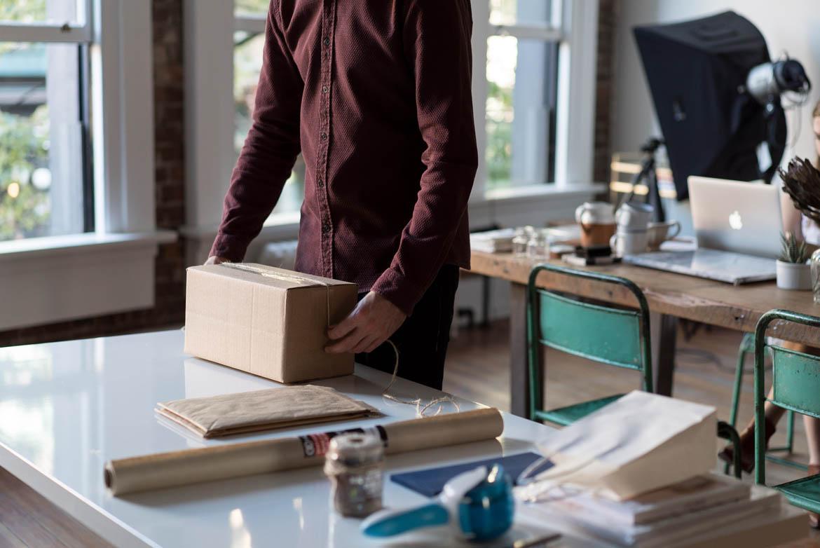 Mann packt kleines Paket mit Paketschnur