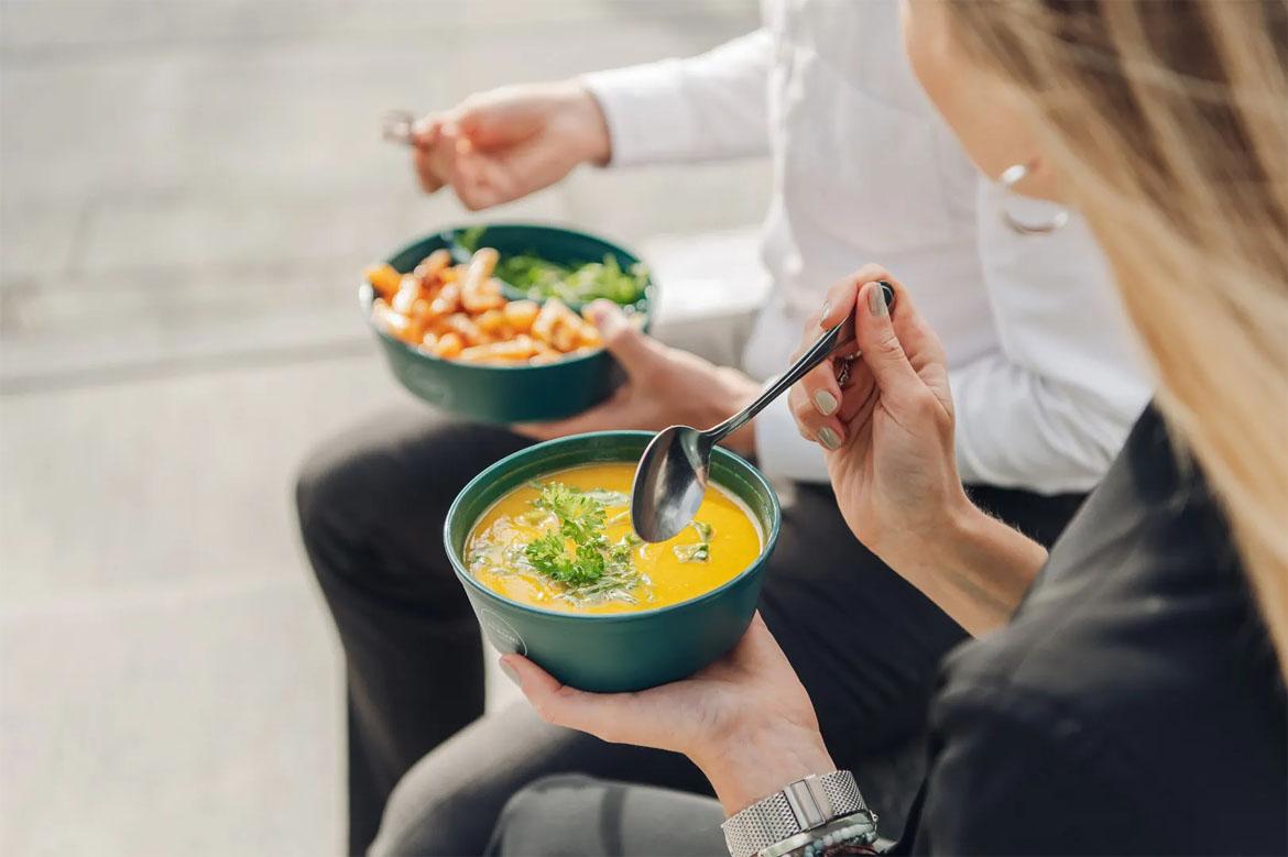 Zwei Personen löffeln Suppe aus einer Mehrwegschale