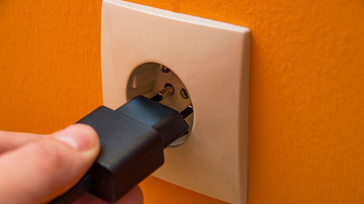 Hand steckt einen Stecker in Steckdose