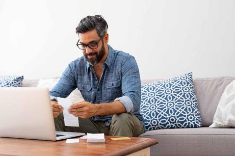 Mann mit Rechnungen vor Laptop